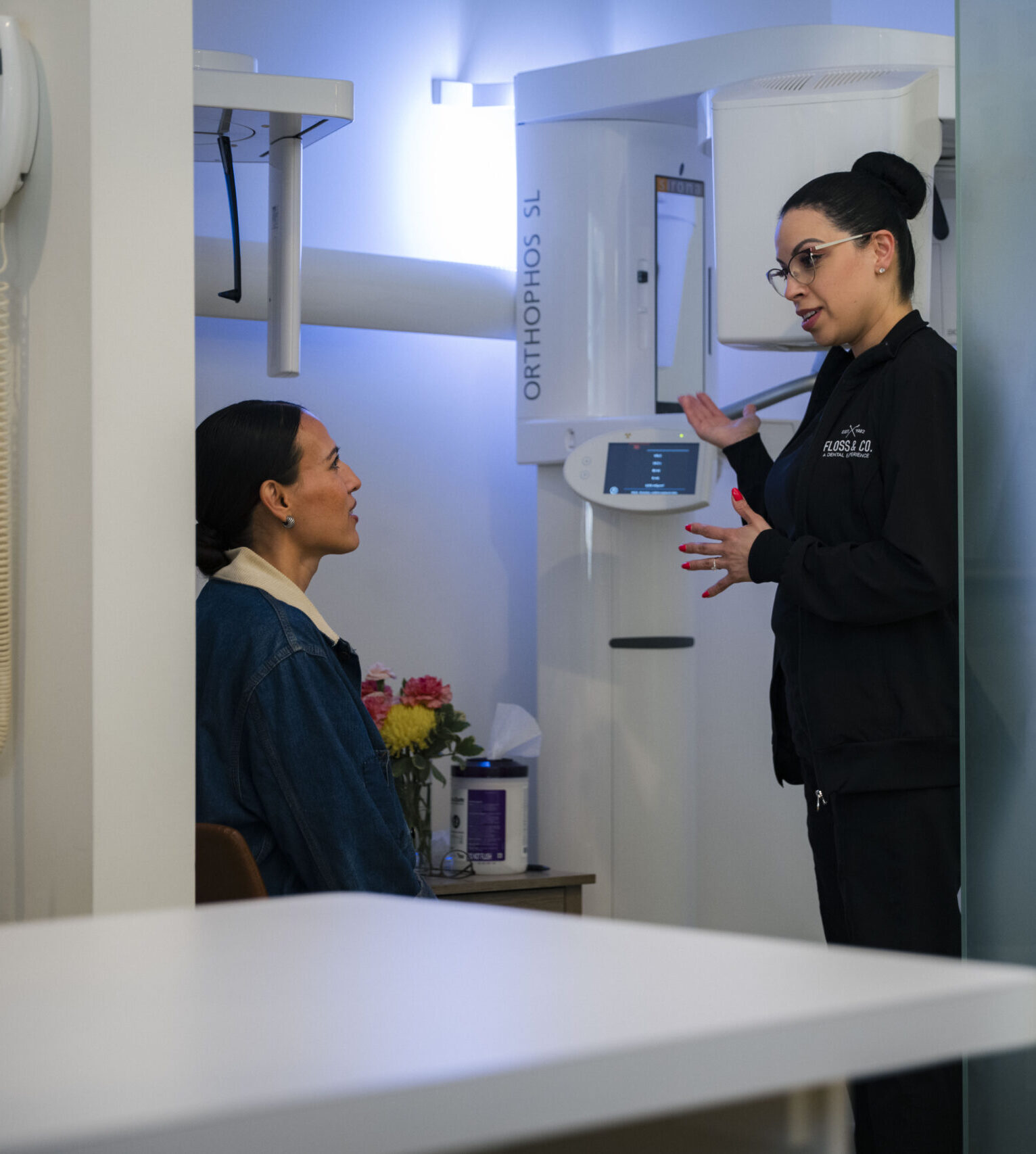 Dental staff member consulting with patient in modern exam room with ORTHOPHOS SL imaging equipment