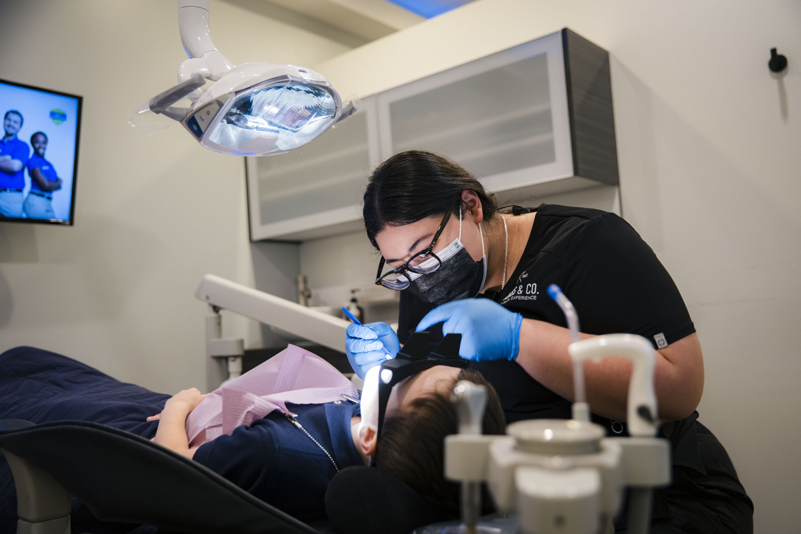 Holistic Airway Dentist clinician performing dental treatment on pediatric patient under chair-side lighting