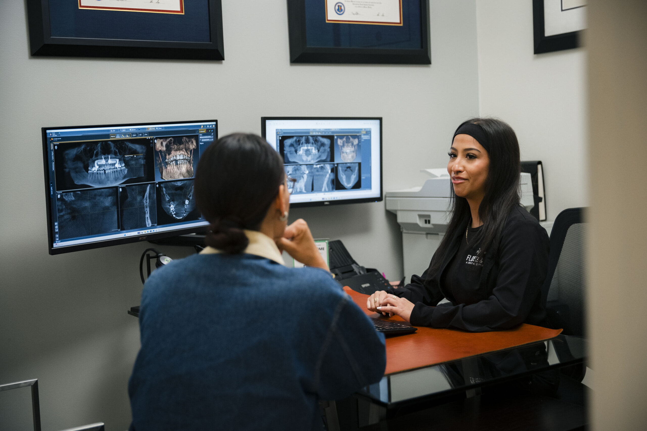 Dentist pointing to dental X-ray images on monitor during patient consultation at The Holistic Airway Dentist.