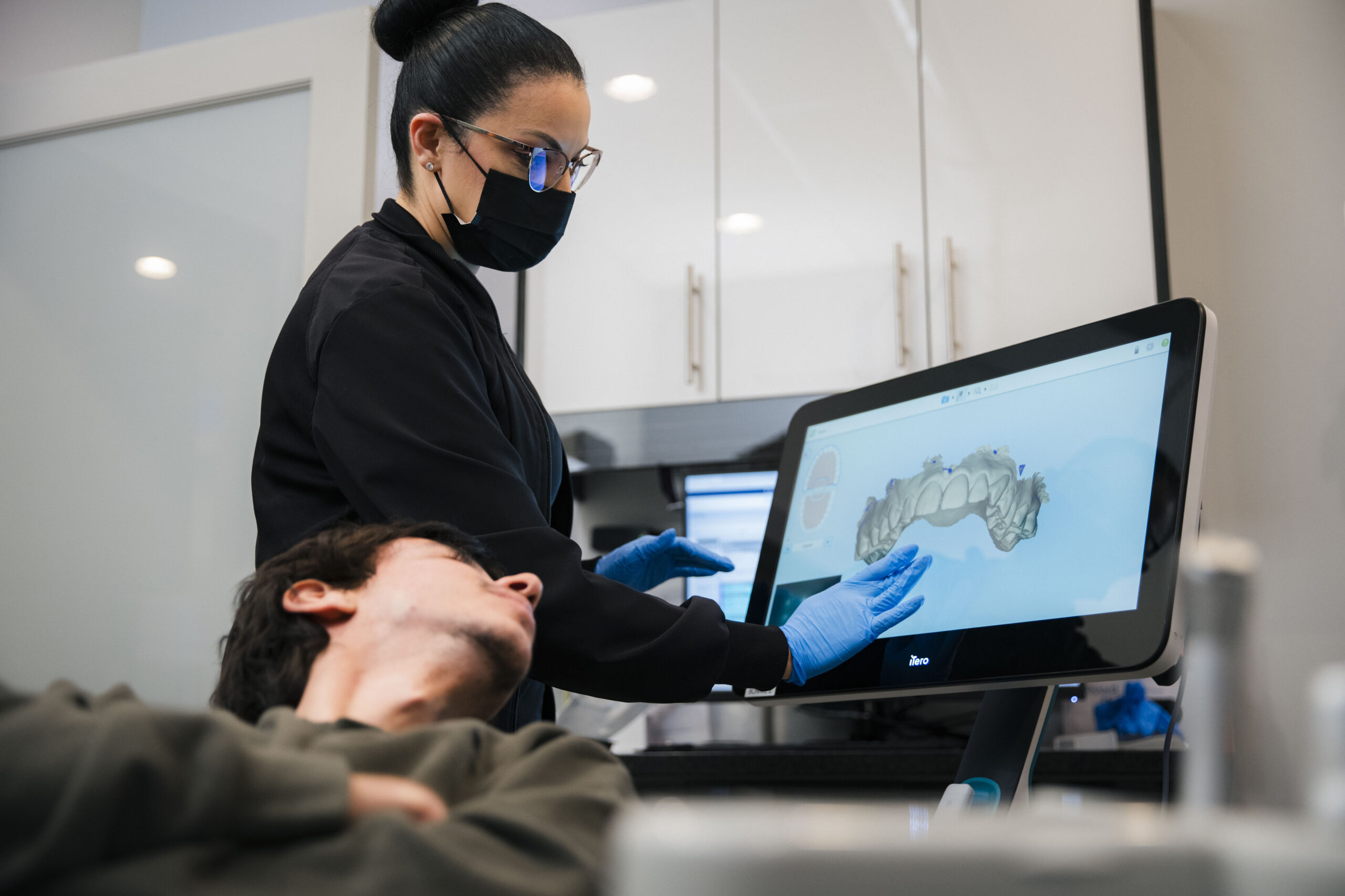 Clinician at The Holistic Airway Dentist displays 3D dental scan on monitor to patient during consultation.