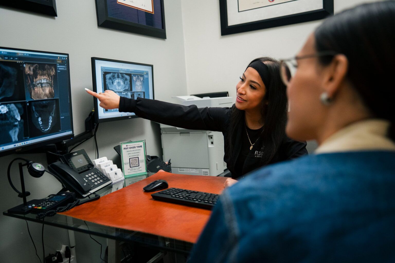 Dental professional pointing at X-ray monitor during patient consultation at The Holistic Airway Dentist office.