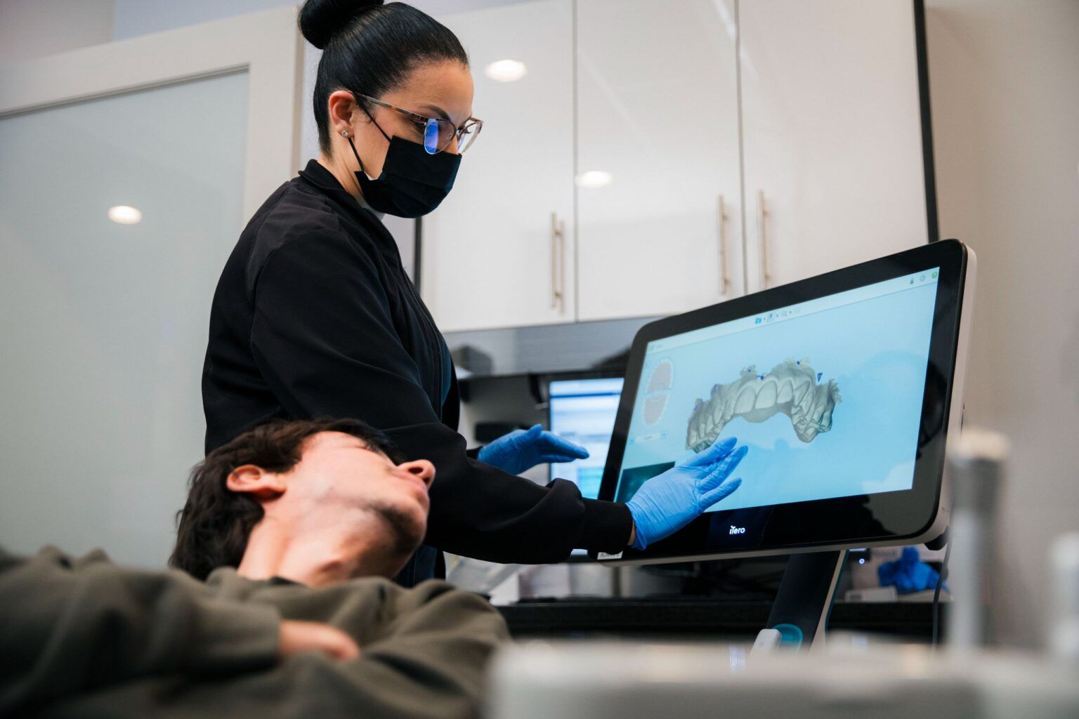 Dental professional showing patient 3D jaw scan on chairside display monitor